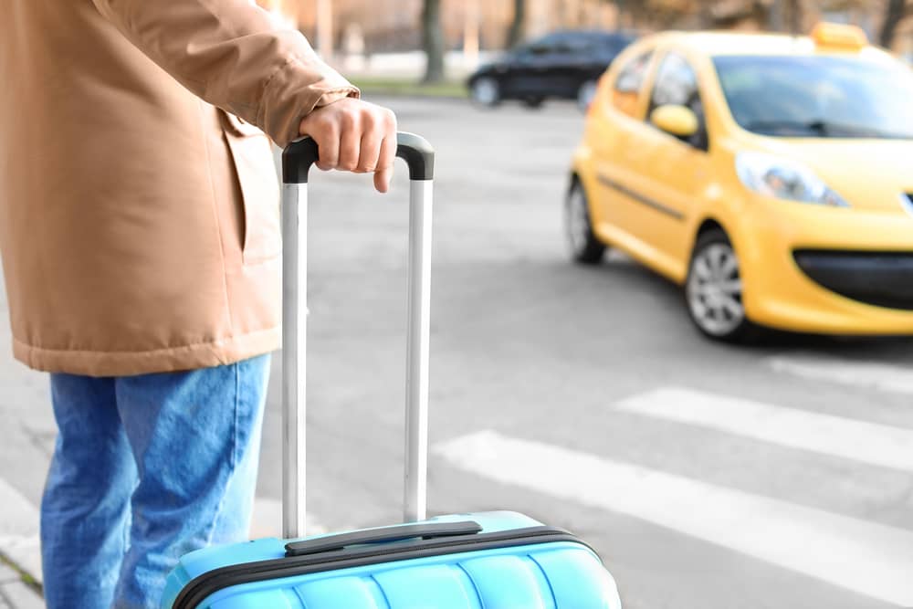 personne avec une valise attendant un taxi
