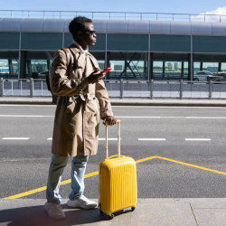 homme avec une valise jaune, attendant un taxi